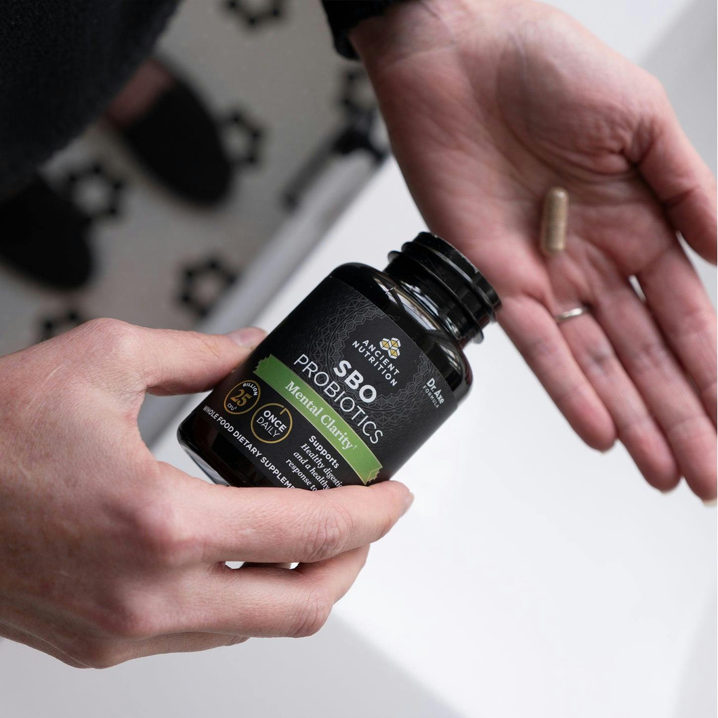 a person putting SBO probiotics mental clarity capsules in their hand