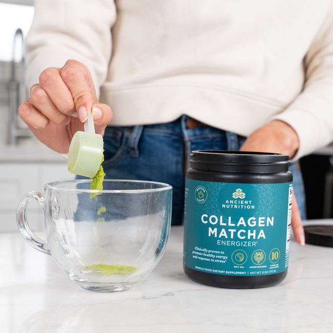 person scooping collagen matcha energizer in a glass cup
