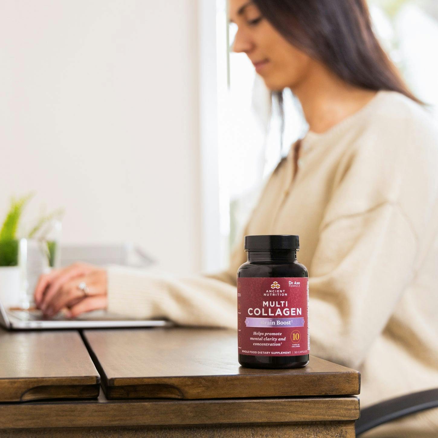 Multi collagen brain boost capsules on desk with woman at computer
