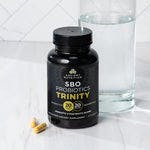 A bottle of SBO Probiotics Trinity Capsules next to a glass of water
