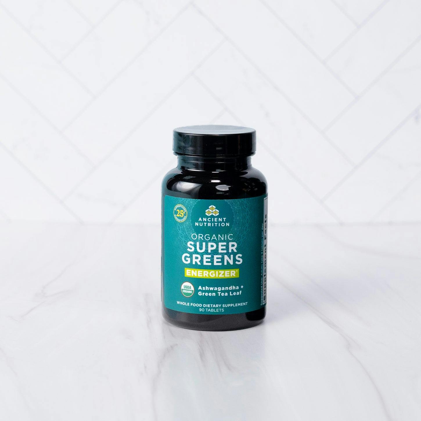 Organic Super Greens Energizer Tablet on a marble countertop