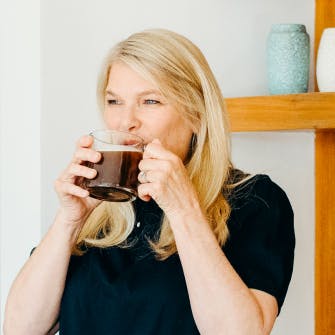 woman drinking coffee from a glass mug