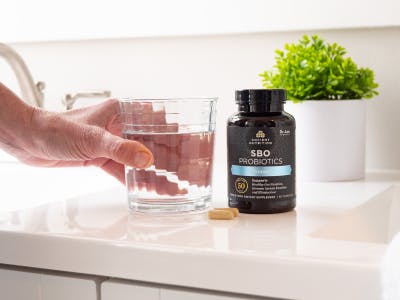 SBO Probiotics Ultimate next to a glass of water