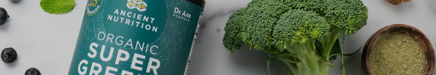 bottle of super greens powder next to broccoli stalk