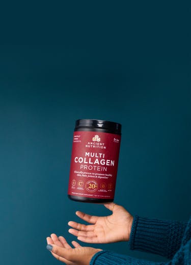 Woman's hands throwing up a container of Ancient Nutrition multi collagen protein on a teal background
