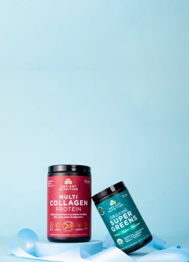 bottle of multi collagen protein and bottle of supergreens on a light blue background