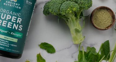 organic supergreens bottle next to broccoli stalk