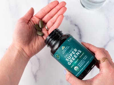 person adding supergreens tablets to their hand