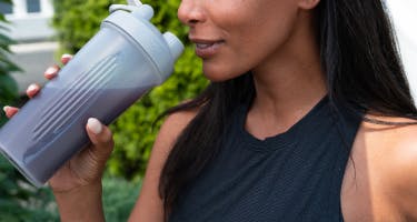 a woman drinking from a shaker bottle