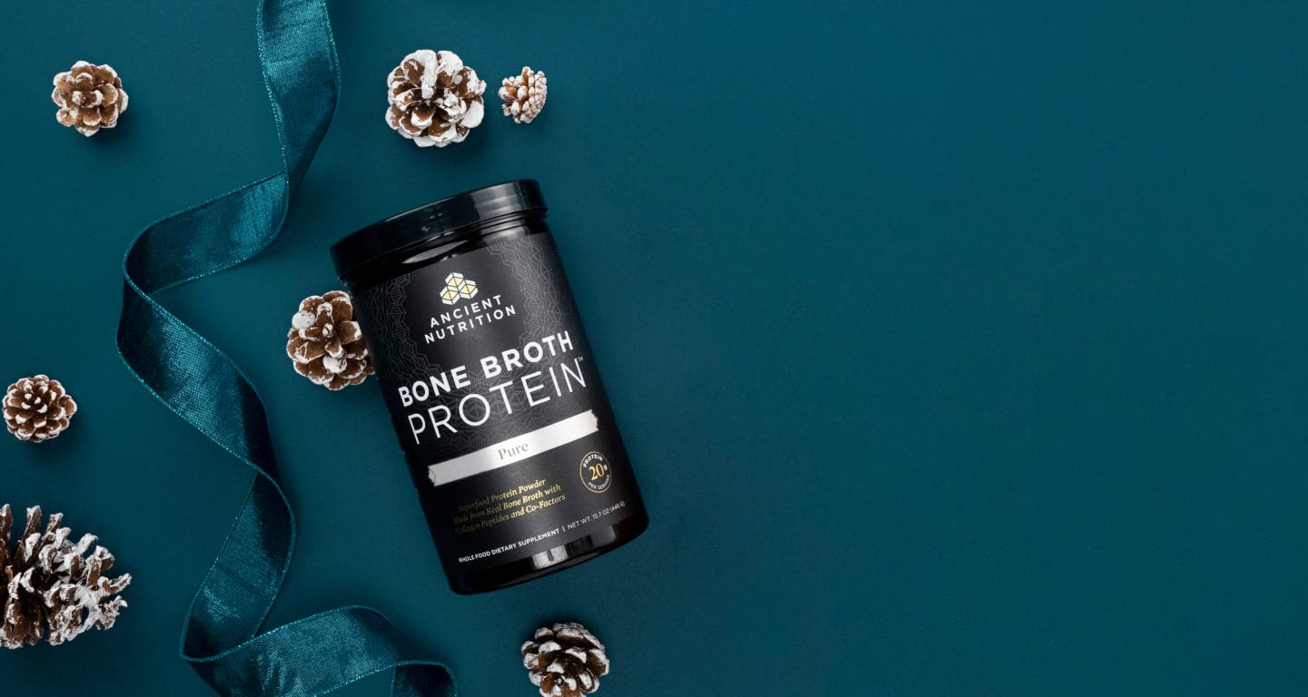 bottle of bone broth protein pure on a blue background with holiday elements 