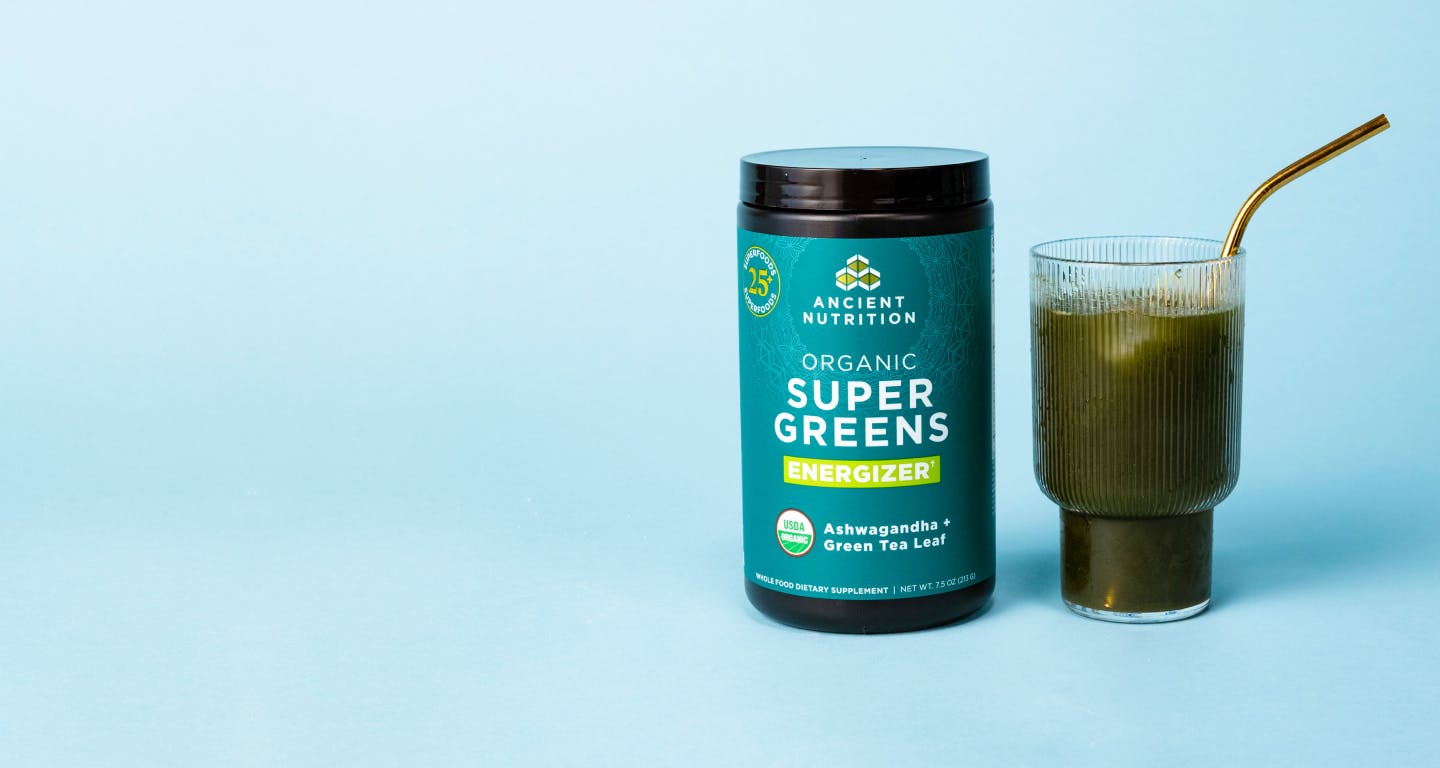 bottle of supergreens next to a glass of green juice